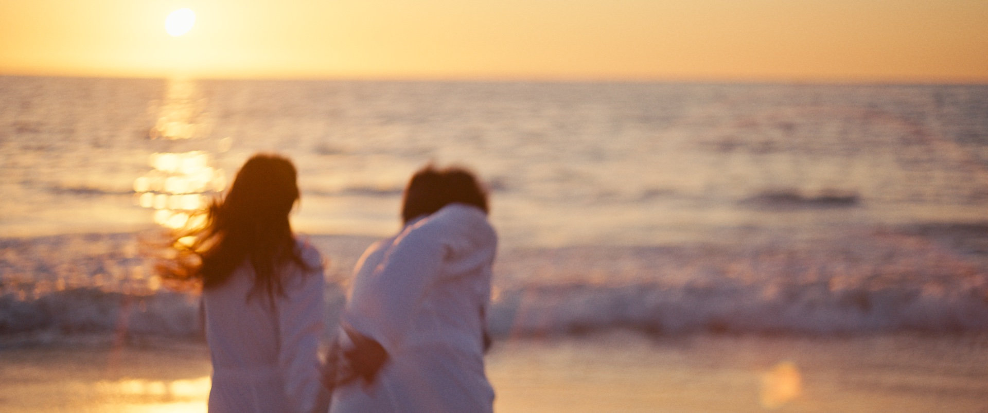 Genesis — Two figures on beach at sunset